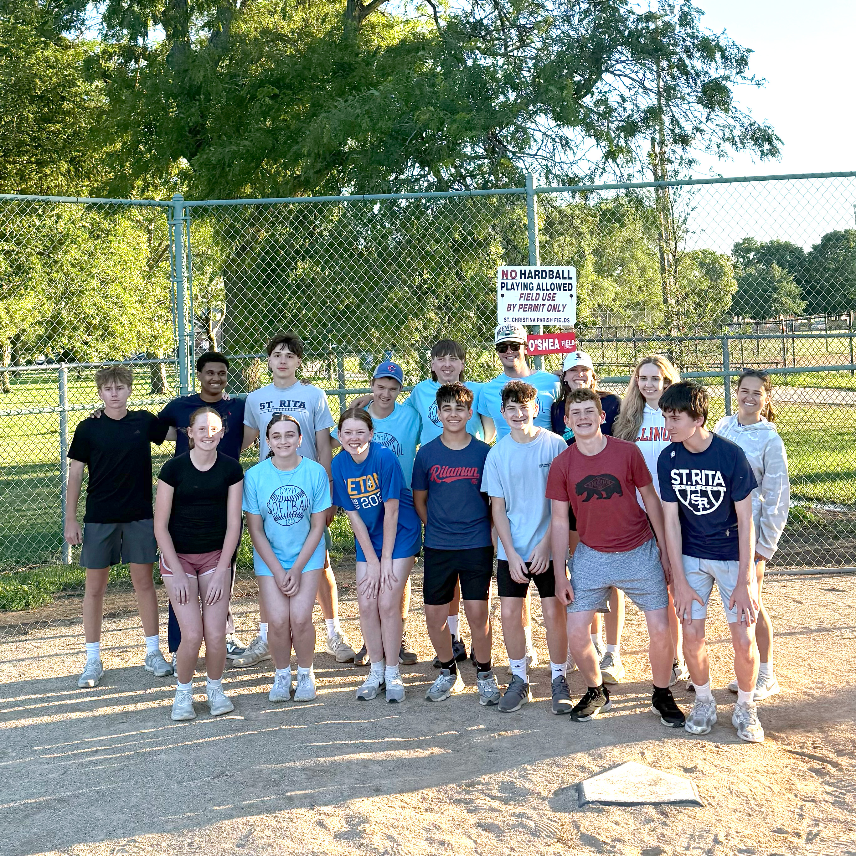 Group of youths lined up on a baseball pitch with trees and a blue sky in the background